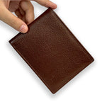 Brown leather wallet held by a hand on a white background